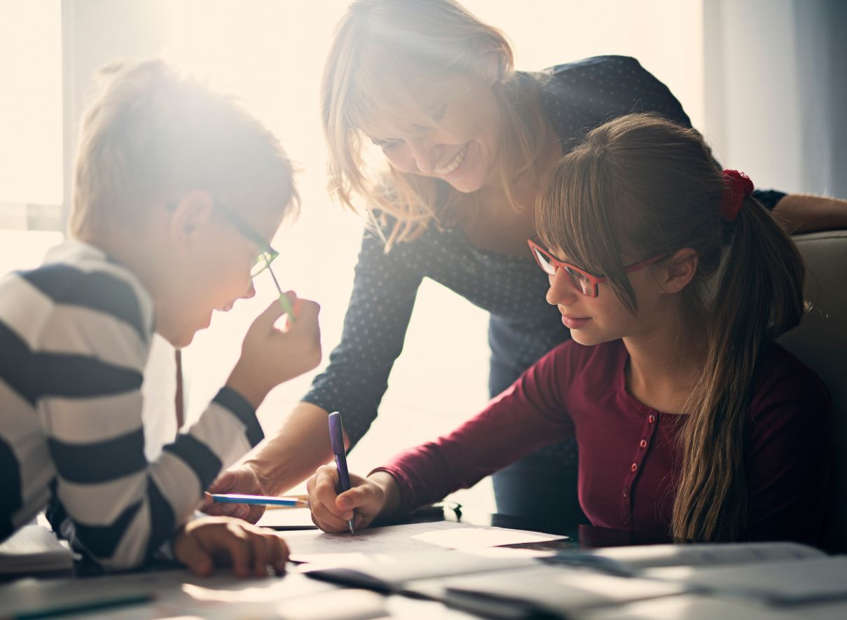 Teacher helping three students with their school work. 