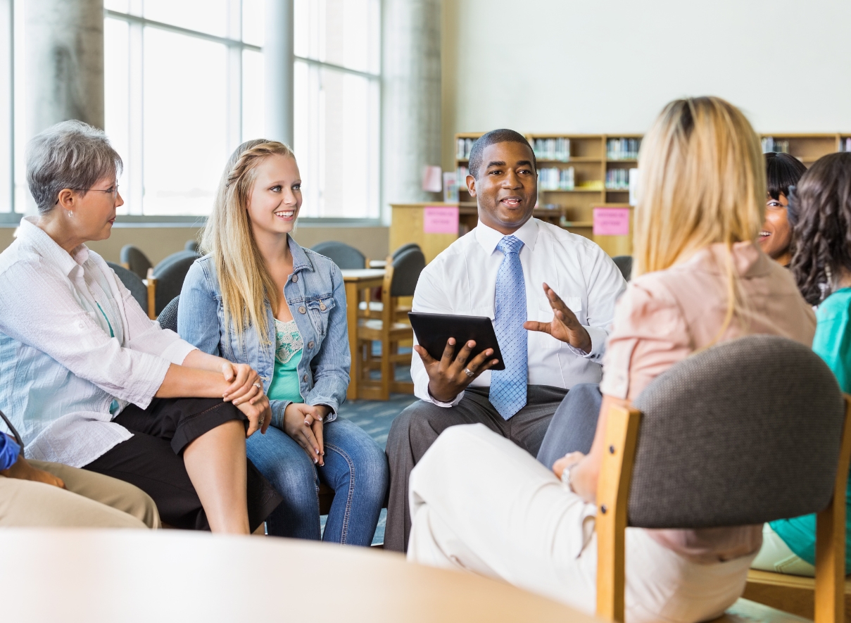 Principal sitting in a circle with a group of teachers.