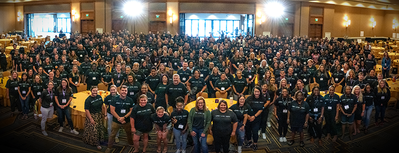 A conference room full of standing educators wearing matching LONG + LIVE + MATH t-shirts